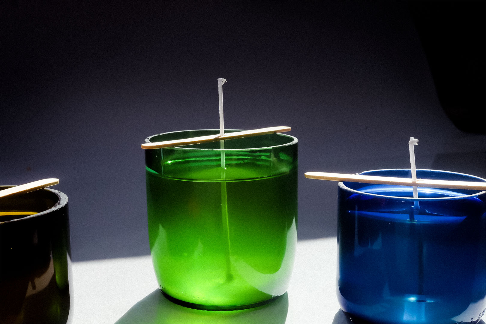 Kolorowe świece sojowe w ciętych butelkach